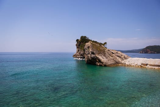 Very beautiful view of the sea and the rock, a small boat near the cliff, aquamarine clear water. Enjoy the view. Montenegro