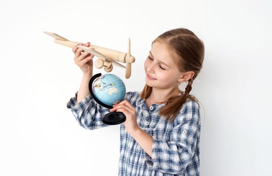 Preteen girl holding globe and wooden plane as symbol of travel and journey. Female child kid discover world and planet