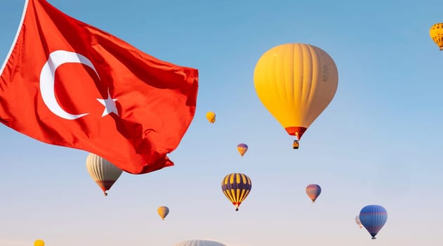 Turkey flag against colorful hot air balloons flying in clear blue sky