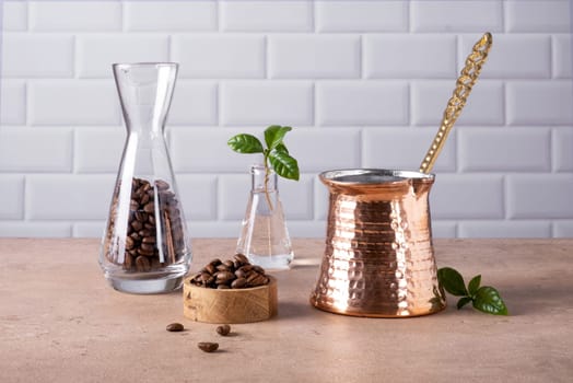 Composition of a traditional Turkish coffee pot cezve, coffee beans and a branch of a coffee tree. Selective focus.