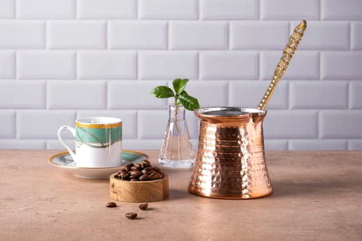 Composition of a traditional Turkish coffee pot cezve, coffee beans and a branch of a coffee tree. Selective focus.