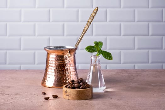Composition of a traditional Turkish coffee pot cezve, coffee beans and a branch of a coffee tree. Selective focus.