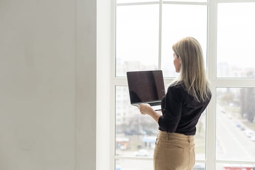 Image of young beautiful joyful woman smiling while working with laptop in office