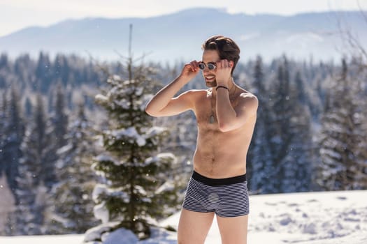 man in shorts and sunglasses on the background of snow-capped mountains