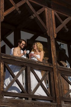 couple wrapped in blankets drinking coffee on the balcony