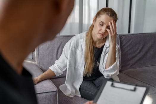 A male psychologist consults a female patient, makes notes. A woman emotionally talks about herself, covering her face with her hands.