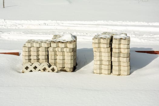 a stack of paving slabs on a construction site covered with snow. Construction and landscaping. High quality photo