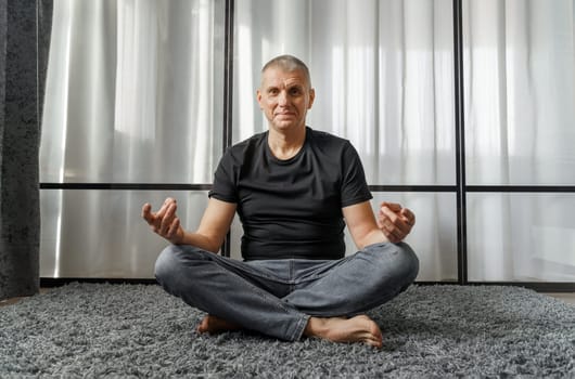 The concept of a healthy lifestyle. Portrait of a man who meditates in the lotus position on a yoga mat during a break at work.