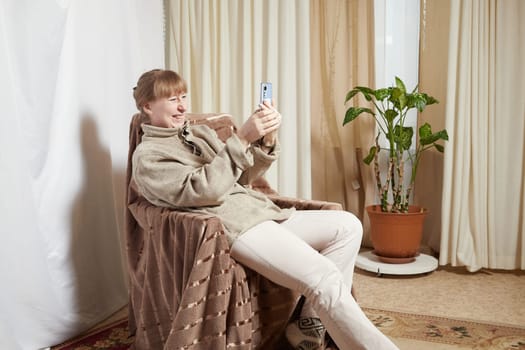 Adult woman with cell phone in room. Middle aged female customer holding smartphone using mobile app, texting message, search commerce offer on phone technology device at homes. Partial focus