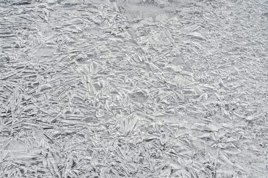 Ice on frozen river, trapped bubbles forming crystal like structures, closeup macro detail from above - abstract winter background.