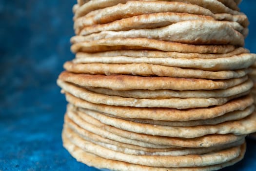 Flatbread lavash, chapati, naan, heap of tortilla on a blue background Homemade flatbread stacked