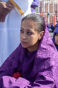 Nazarene woman in a Holy Week procession sitting and tired. High quality photo