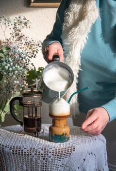 woman pouring frothed milk coffee with tapioca into morning coffee for breakfast, retro still life High quality photo