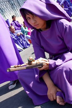 nazarena with a cross of jesus christ in her hands sitting before a procession. High quality photo