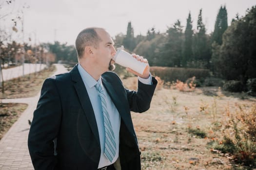 Mature entrepreneur drink coffee in autumn park. Senior executive rest in city park.