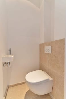 a toilet in the corner of a bathroom with beige tiles on the walls, and a white wall mounted above it