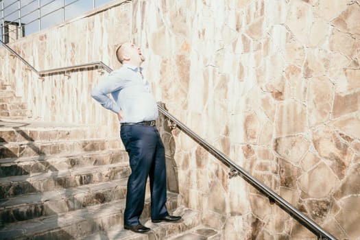 Portrait of a senior professional man in a suit with various problems. A middle-aged businessman with a briefcase descends the stairs.