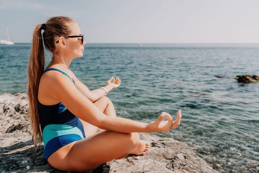 Woman sea yoga. Back view of free calm happy satisfied woman with long hair standing on top rock with yoga position against of sky by the sea. Healthy lifestyle outdoors in nature, fitness concept.
