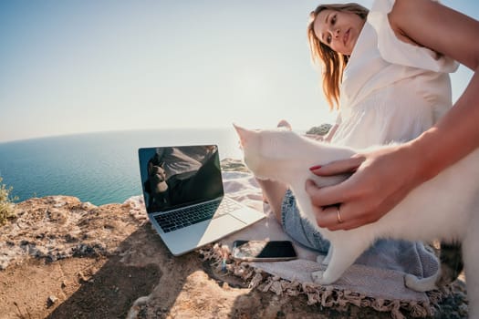 Woman sea laptop. Business woman in yellow hat working on laptop by sea. Close up on hands of pretty lady typing on computer outdoors summer day. Freelance, digital nomad, travel and holidays concept.