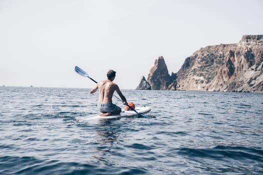 Side view foto of a man swiming and relaxing on the sup board. Sportive man in the sea on the Stand Up Paddle Board SUP. The concept of an active and healthy life in harmony with nature