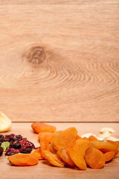 Dried fruits and nuts on wooden background in studio setup. Raw healthy lifestyle