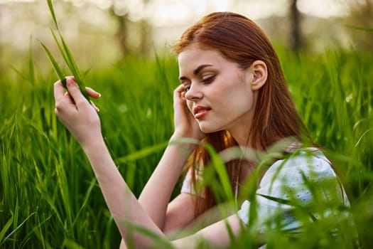 pensive woman with red hair sits in tall grass. High quality photo
