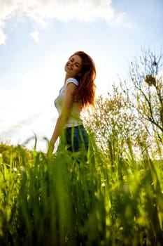 cute woman in summer clothes standing in a field of tall grass, bottom view. High quality photo