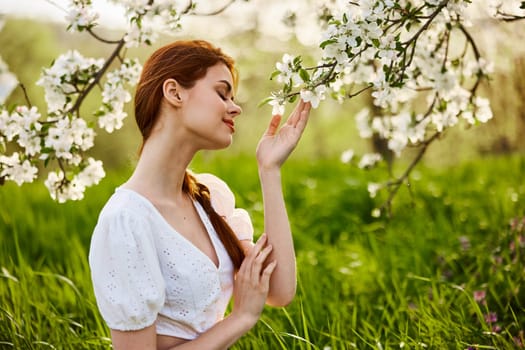 attractive fresh woman posing for a portrait of a flowering Apple tree and looks away. A vivid portrait in Sunny weather. High quality photo