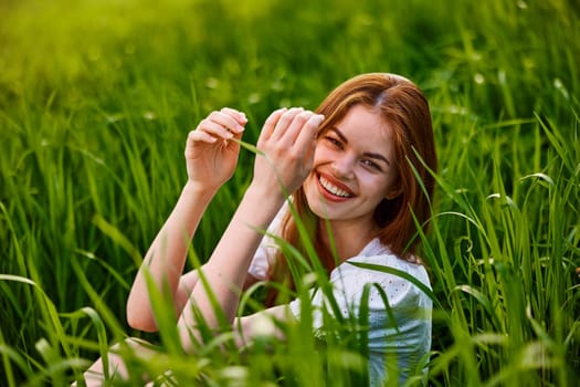 portrait of laughing woman sitting in tall grass. High quality photo
