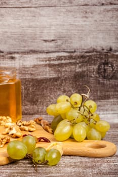 Nuts, honey and grape on wooden background in studio photo