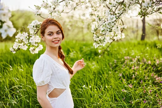 a young woman in a light summer dress is resting sitting under a flowering tree. High quality photo