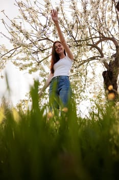 cute woman in light clothes posing next to a flowering tree in the countryside. High quality photo