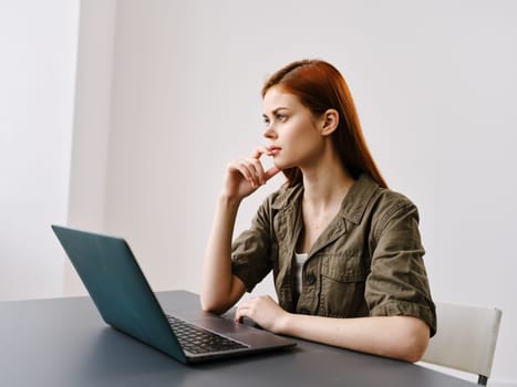serious, pensive woman working in a bright office behind a laptop. High quality photo