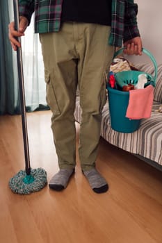 unrecognizable man holding a mop and a bucket with cleaning products, home cleaning concept