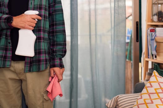 unrecognizable person holding cleaning spray and rag, home cleaning concept, copy space for text