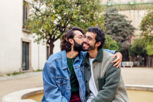 young man kissing tenderly his boyfriend's cheek, concept of urban lifestyle and love between people of the same sex, copy space for text