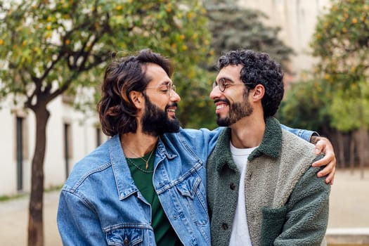 young couple of gay men looking into each other's eyes tenderly, concept of urban lifestyle and love between people of the same sex, copy space for text