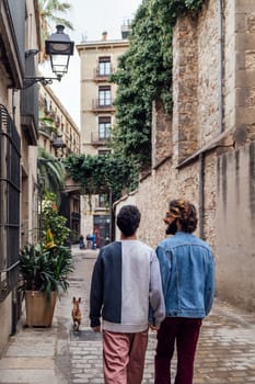 rear view of a gay male couple strolling happy down a cobbled street holding hands, concept of leisure and love between people of the same sex, copy space for text
