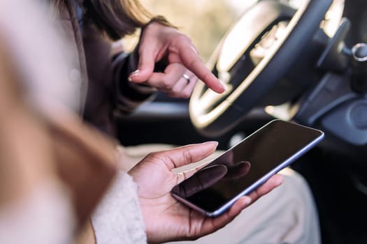 close up of the hands of two young women using road navigation at phone on a road trip, concept of adventure and travel technology