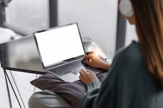 Beautiful Asian Woman smile and relaxing at home and using laptop computer sitting on cozy sofa.