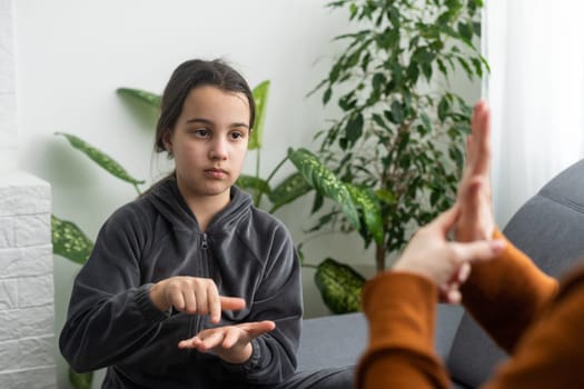 daughter talk with middle aged mother people using sign language, family sitting on armchair side view, teacher teach teenager deaf-mute girl to visual-manual gestures symbols concept image.