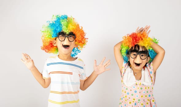 April Fool's Day. Two brothers funny kid little girl clown wears curly wig colorful big nos and glasses and has mustache playing fool isolated on white background copy space, Happy child festive decor