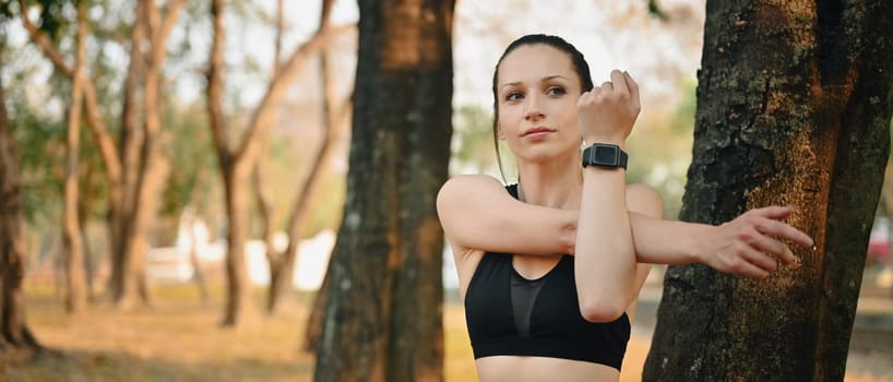 Motivated sporty woman stretching arms before workout routine outdoor. Fitness, training and healthy lifestyle concept.