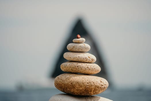 Pyramid stones on the seashore with warm sunset on the sea background. Happy holidays. Pebble beach, calm sea, travel destination. Concept of happy vacation on the sea, meditation, spa, calmness.