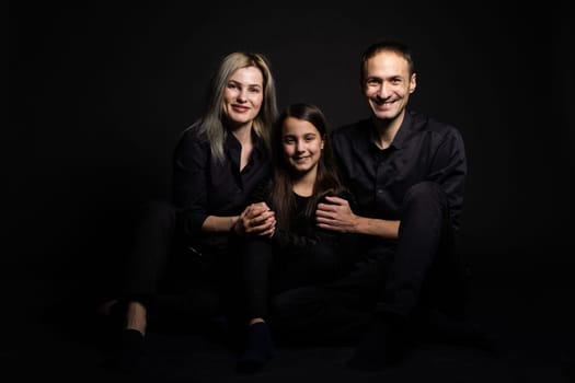 Happy young family with one child having fun together isolated on black