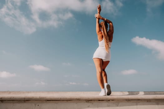 Fitness woman sea. Outdoor workout on yoga mat in park near to ocean beach. Female fitness pilates yoga routine concept. Healthy lifestyle. Happy fit woman exercising with rubber band in park.