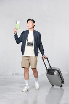 Portrait of happy young guy holding passport and boarding pass against white background