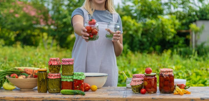 A woman preserves vegetables in jars. Selective focus. Food.