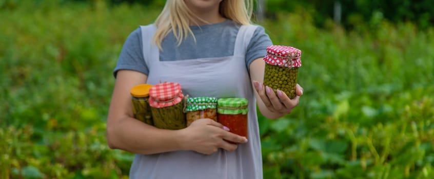 A woman preserves vegetables in jars. Selective focus. Food.