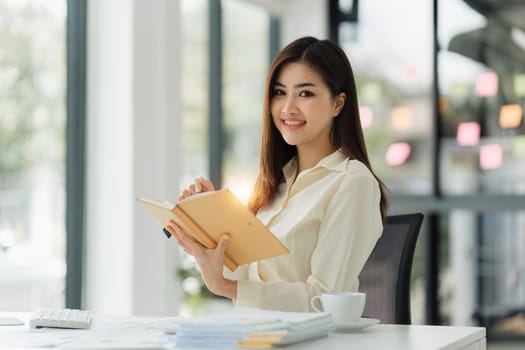 Beautiful Asian Banker or Accountant makes financial report and tax, analyzes profits. Accountant checks status of financial.